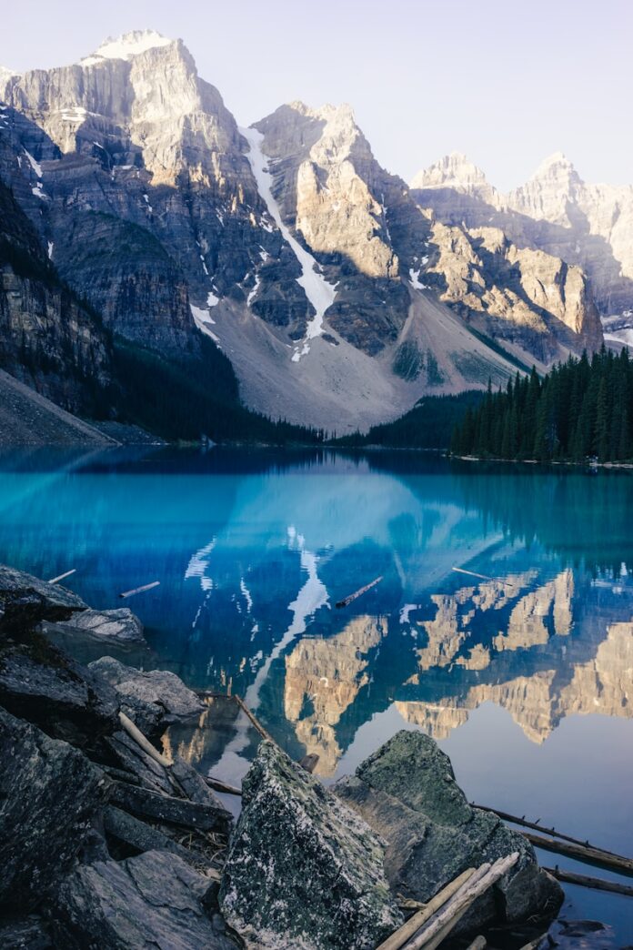 lake surrounded by green trees and snow covered mountains during daytime