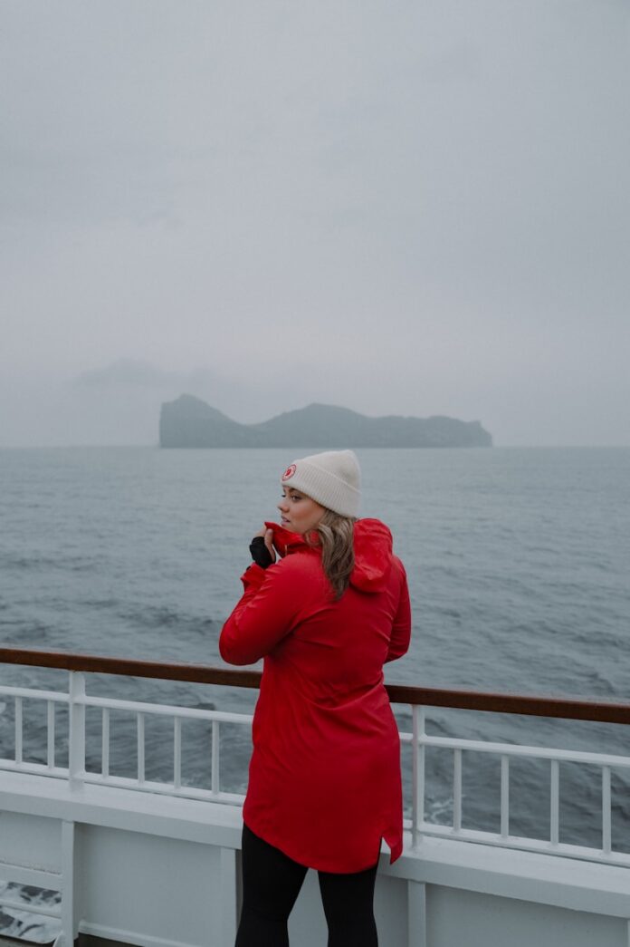 A woman in a red coat standing on a boat