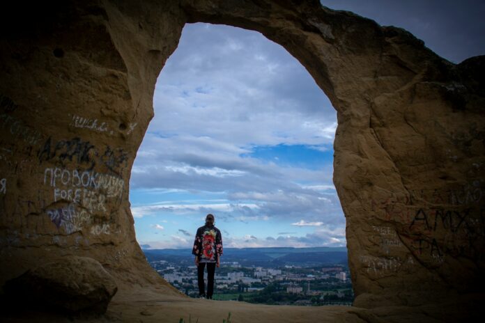 a person standing in a cave with graffiti on it